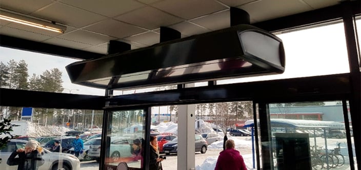 Ilmaverhokone myymälän sisäänkäynnin yläpuolella sisältä kuvattuna